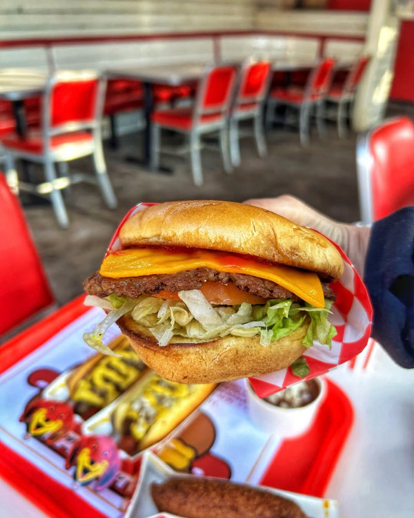 Vegan burger with plant-based patty, vegan cheese, lettuce, and tomato in a soft bun at Tail O’ The Pup.