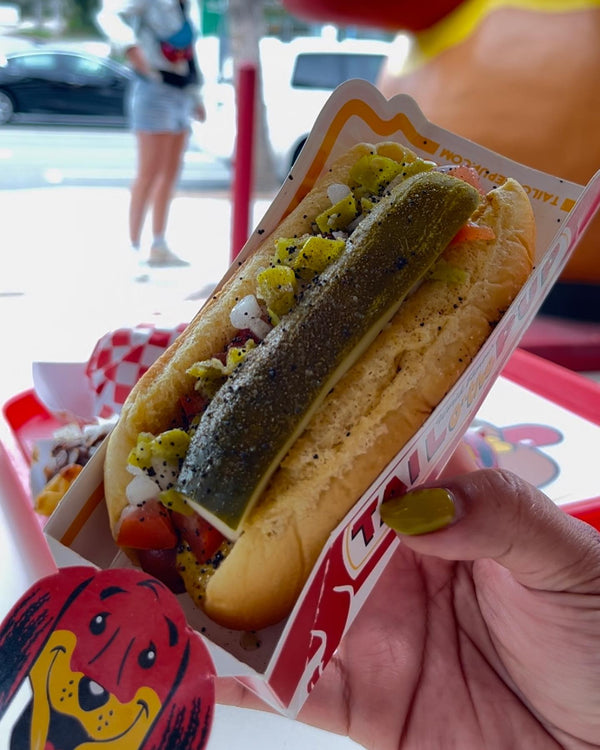 A woman holding a Chicago-style Hot Dog from Tail O’ The Pup.