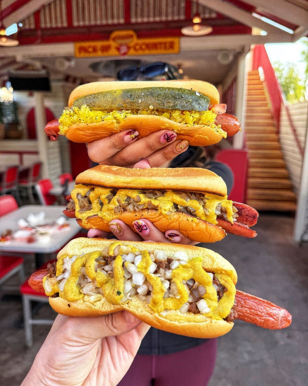 Stack of hot dogs held in front of Tail O’ The Pup hot dog stand.