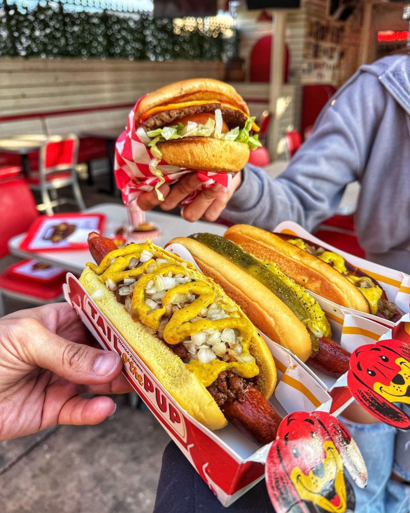  Two lovely people casually dining at Tail O’ The Pup with hot dogs and burgers.