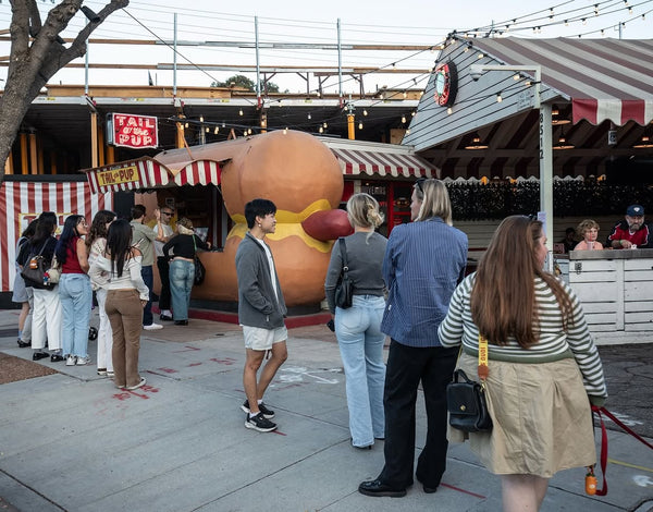 Crowd gathered outside the iconic giant hot-dog-shaped Tail O' The Pup stand in West Hollywood, Los Angeles.