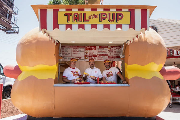 Three Tail O’ The Pup staff members standing inside the iconic hot-dog-shaped restaurant in West Hollywood.